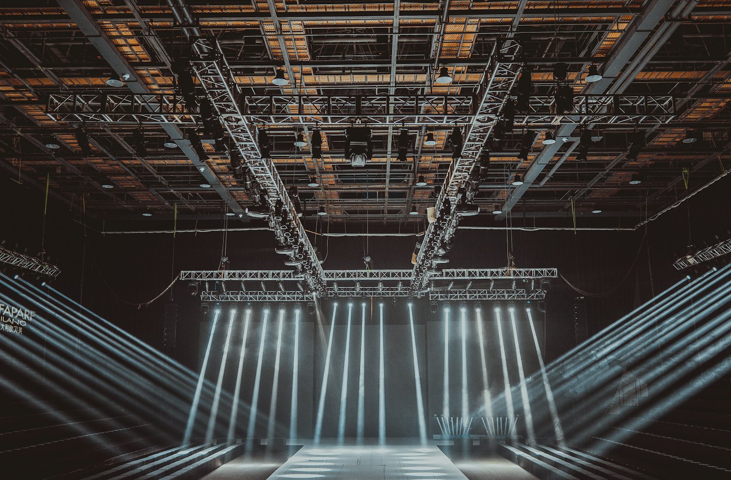 Empty fashion runway with bright spotlights shining on the polished floor.