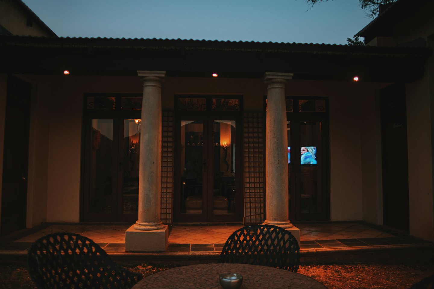 Two chairs on a patio outside a building at twilight.