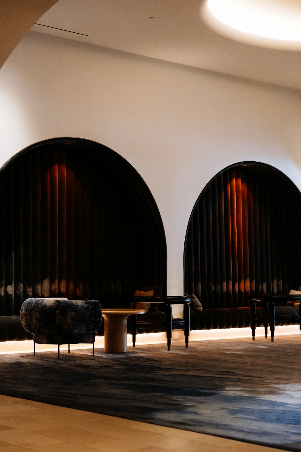Modern lounge with velvet seating alcoves and wood furniture.