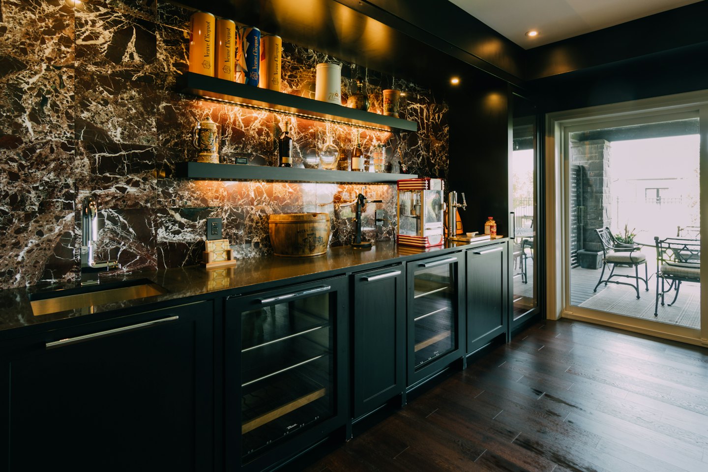 Modern home bar featuring marble backsplash and golden countertop.