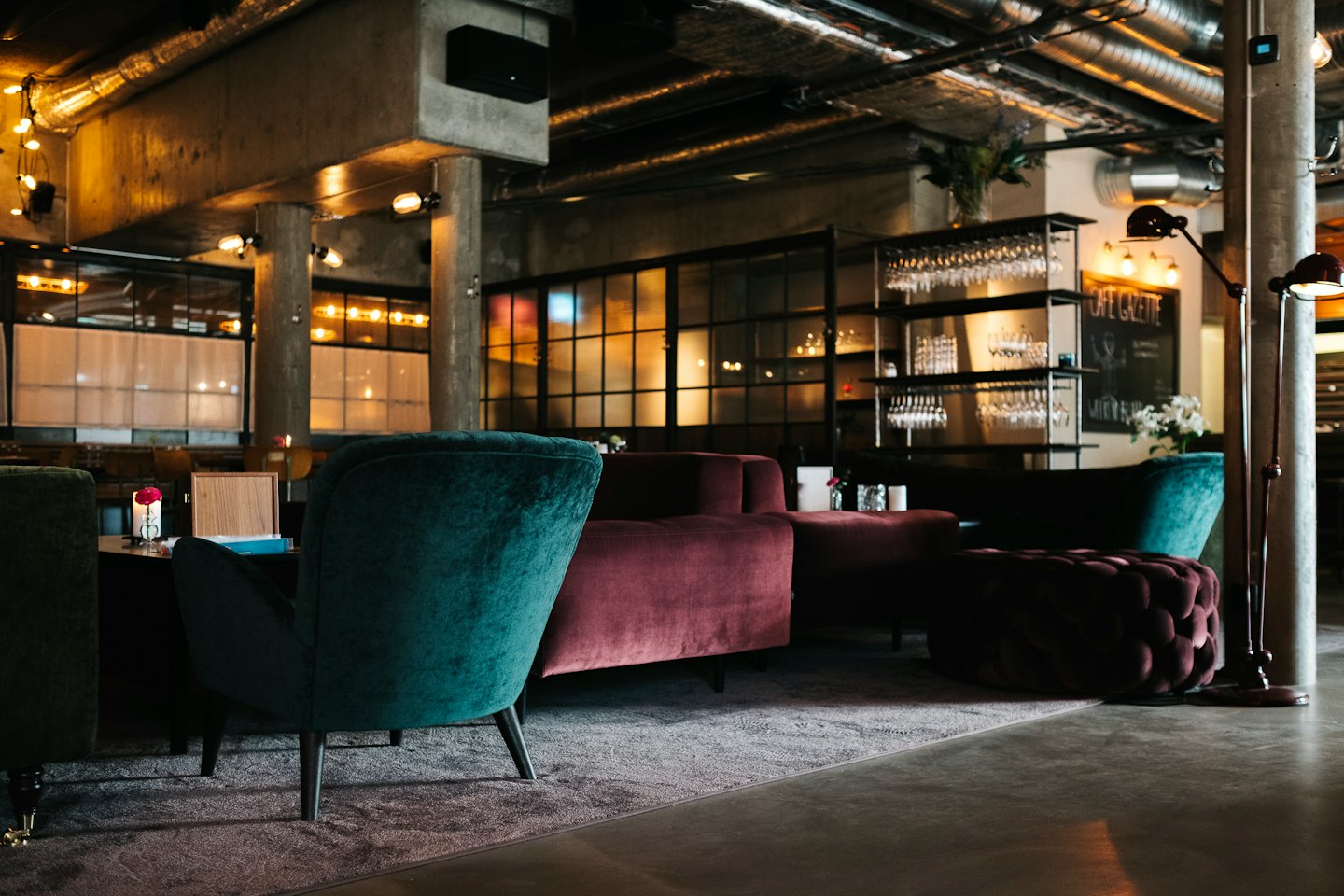 Stylish lounge with teal armchairs and burgundy sofas.